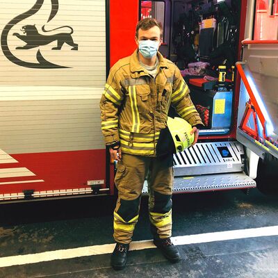 Benjamin Treiber im Schutzanzug vor einem Feuerwehrauto
